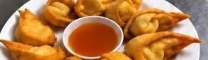 Fried crab rangoon on a plate with a bowl of sweet chili sauce