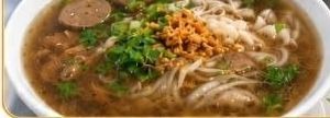 A bowl of pho with noodles, sliced beef, herbs and fried onion